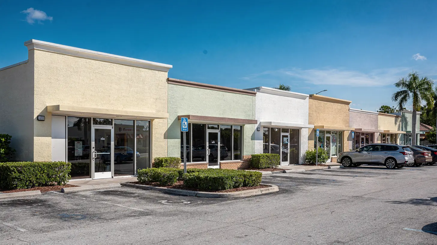 A row of small independent Southwest Florida storefronts side by side in bright morning sun, each pale stucco frontage much like the next.